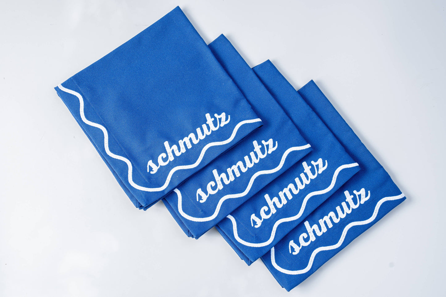 Set of 4 embroidered cotton napkins with a wavy border design, available in Bubbe Blue and Oy Vey Navy. Ideal for dinner parties, these 15-inch napkins are perfect for wiping up schmutz. Machine washable and ready for gifting, wrapped in ribbon.