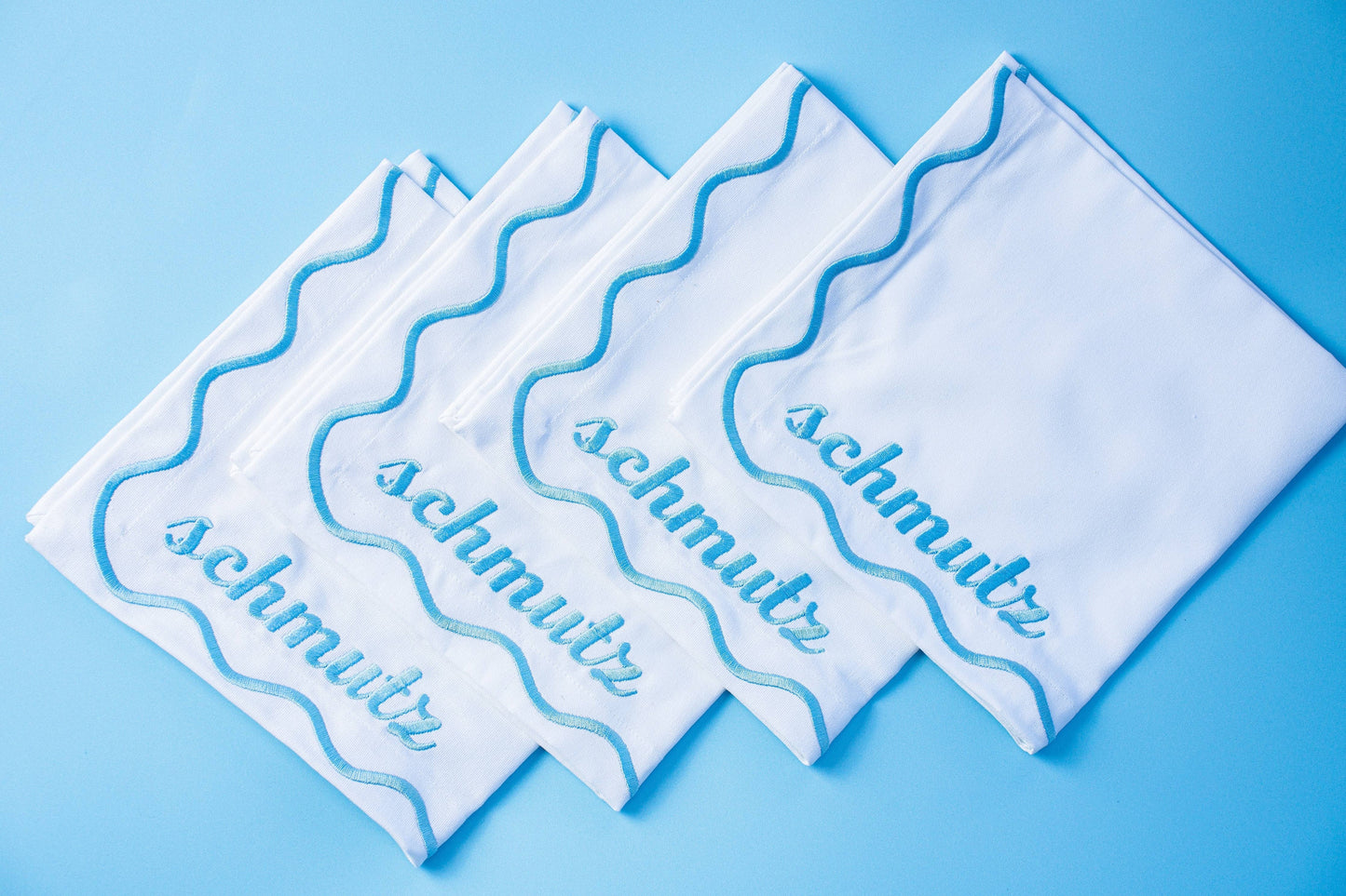 Set of 4 embroidered cotton napkins with a wavy border design, available in Bubbe Blue and Oy Vey Navy. Ideal for dinner parties, these 15-inch napkins are perfect for wiping up schmutz. Machine washable and ready for gifting, wrapped in ribbon.