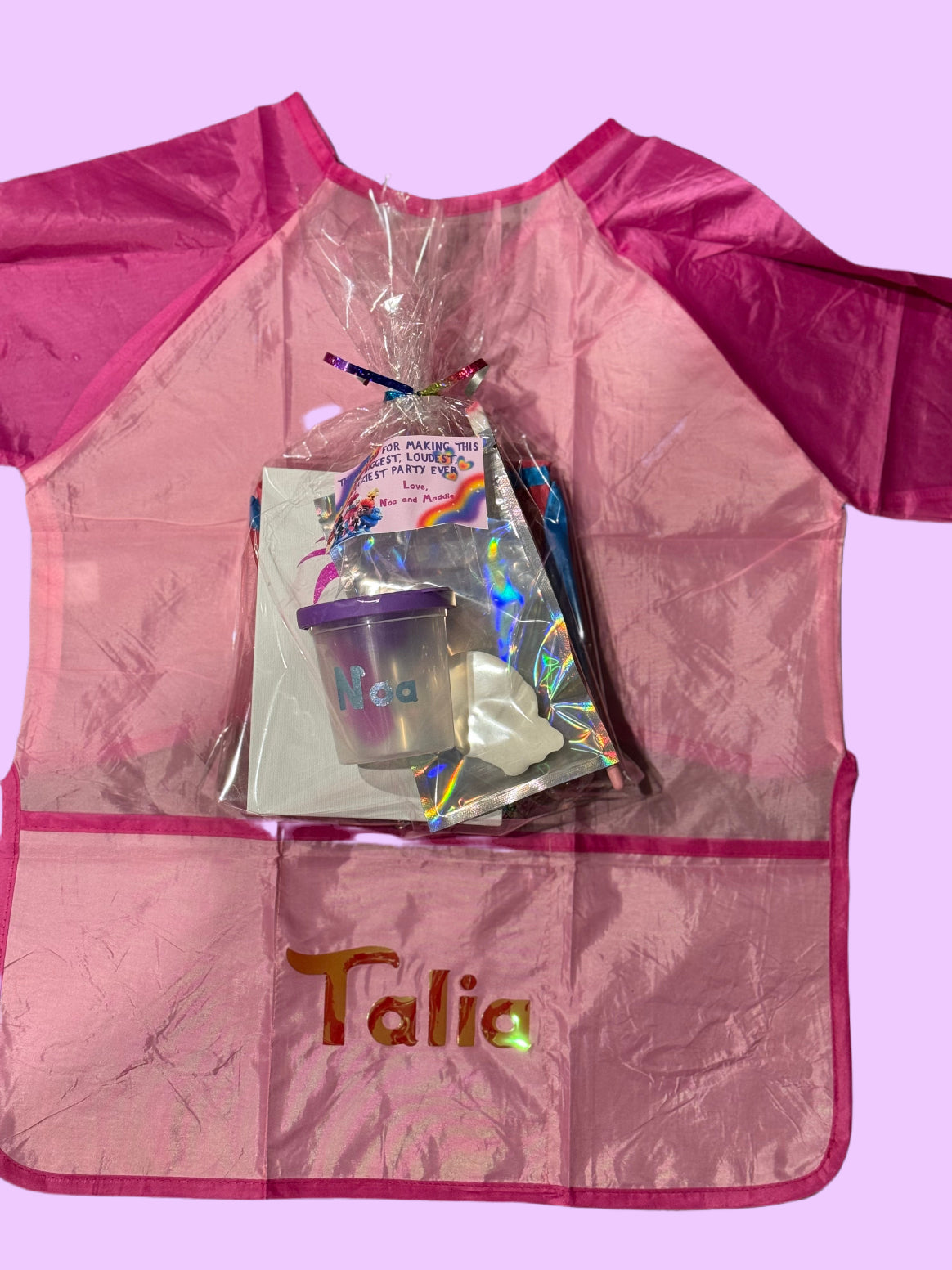 Custom Artist Smock for kids featuring a protective waterproof design, personalized with the child’s name. Ideal for pint-sized Picassos and little artists, this lightweight and durable plastic apron protects clothing from paint and glue. It includes a big front pocket for paint supplies and comes in various colors and font styles.