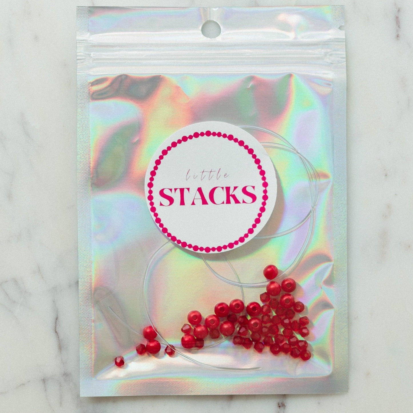 Friendship bracelet kit for SWIFTIES featuring red pearls and red crystal beads, perfect for crafting cute and trendy jewelry. This DIY kit comes in a silver bag with clear string and is designed to make approximately 2+ bracelets. Ideal for creative activities, it is suitable for older kids under adult supervision, as it contains small parts that may pose a choking hazard for children under 3. Enjoy making stylish friendship bracelets with friends while showcasing your love for the 'Red' era!