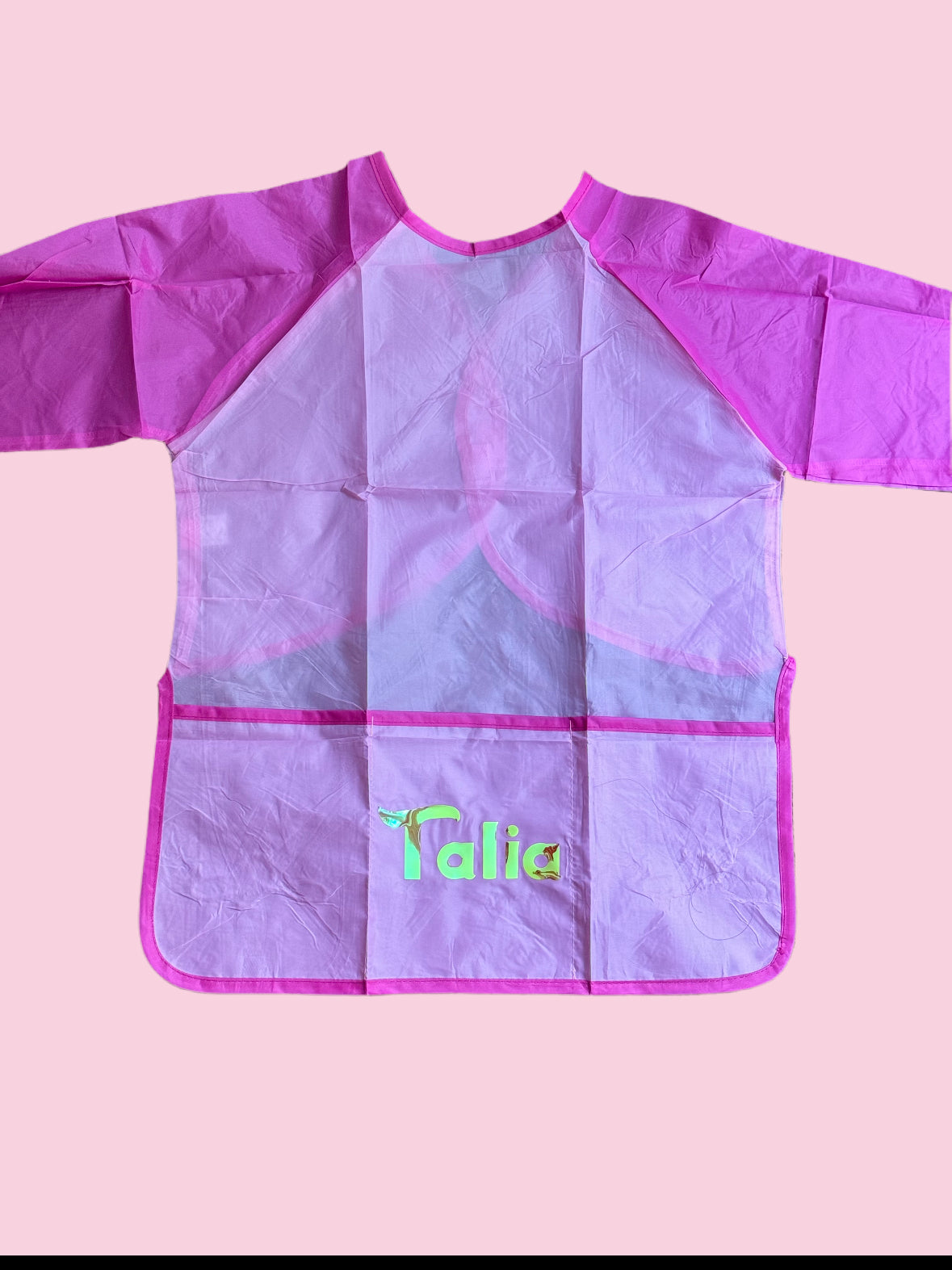 Custom Artist Smock for kids featuring a protective waterproof design, personalized with the child’s name. Ideal for pint-sized Picassos and little artists, this lightweight and durable plastic apron protects clothing from paint and glue. It includes a big front pocket for paint supplies and comes in various colors and font styles.