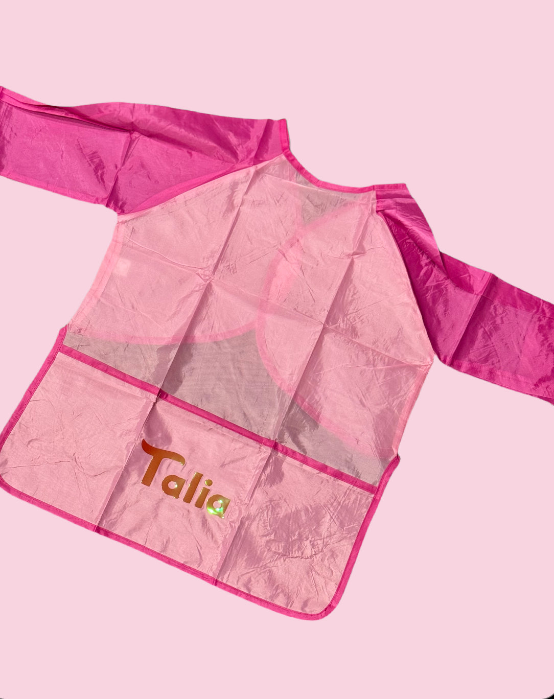 Custom Artist Smock for kids featuring a protective waterproof design, personalized with the child’s name. Ideal for pint-sized Picassos and little artists, this lightweight and durable plastic apron protects clothing from paint and glue. It includes a big front pocket for paint supplies and comes in various colors and font styles.