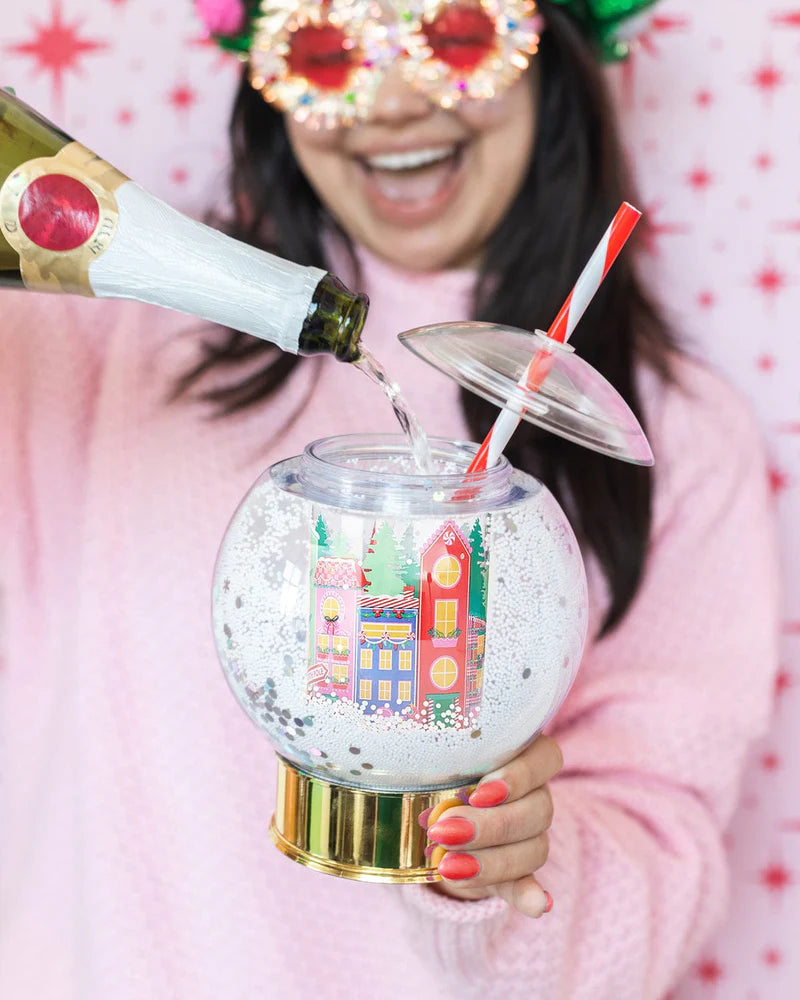 Shake up your holiday drinks with this 12 oz snow globe-shaped cup, featuring a holiday village and shakeable confetti. Perfect for festive parties or as a unique gift. BPA-free and hand wash only. Dimensions: 10.5" x 5" x 5" (including straw).