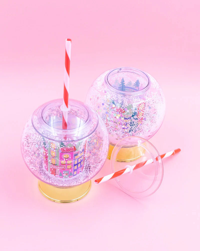 Shake up your holiday drinks with this 12 oz snow globe-shaped cup, featuring a holiday village and shakeable confetti. Perfect for festive parties or as a unique gift. BPA-free and hand wash only. Dimensions: 10.5" x 5" x 5" (including straw).