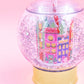 Shake up your holiday drinks with this 12 oz snow globe-shaped cup, featuring a holiday village and shakeable confetti. Perfect for festive parties or as a unique gift. BPA-free and hand wash only. Dimensions: 10.5" x 5" x 5" (including straw).
