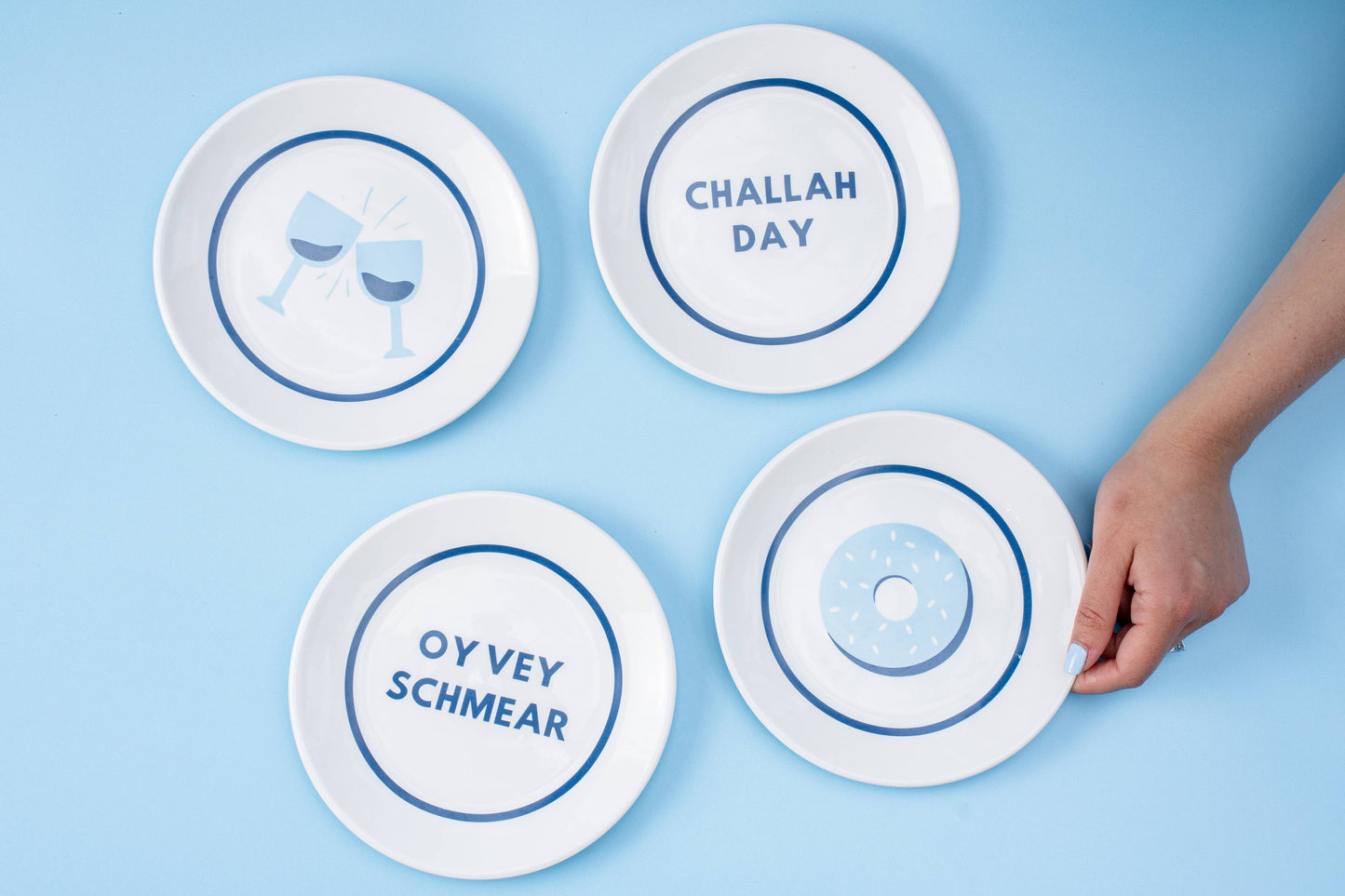 Hanukkah gift set featuring 4 porcelain nosh plates and 4 cotton/linen cocktail napkins, each with playful designs. Perfect for festive meals and gifting. Includes a custom gift box, ideal for holiday celebrations.