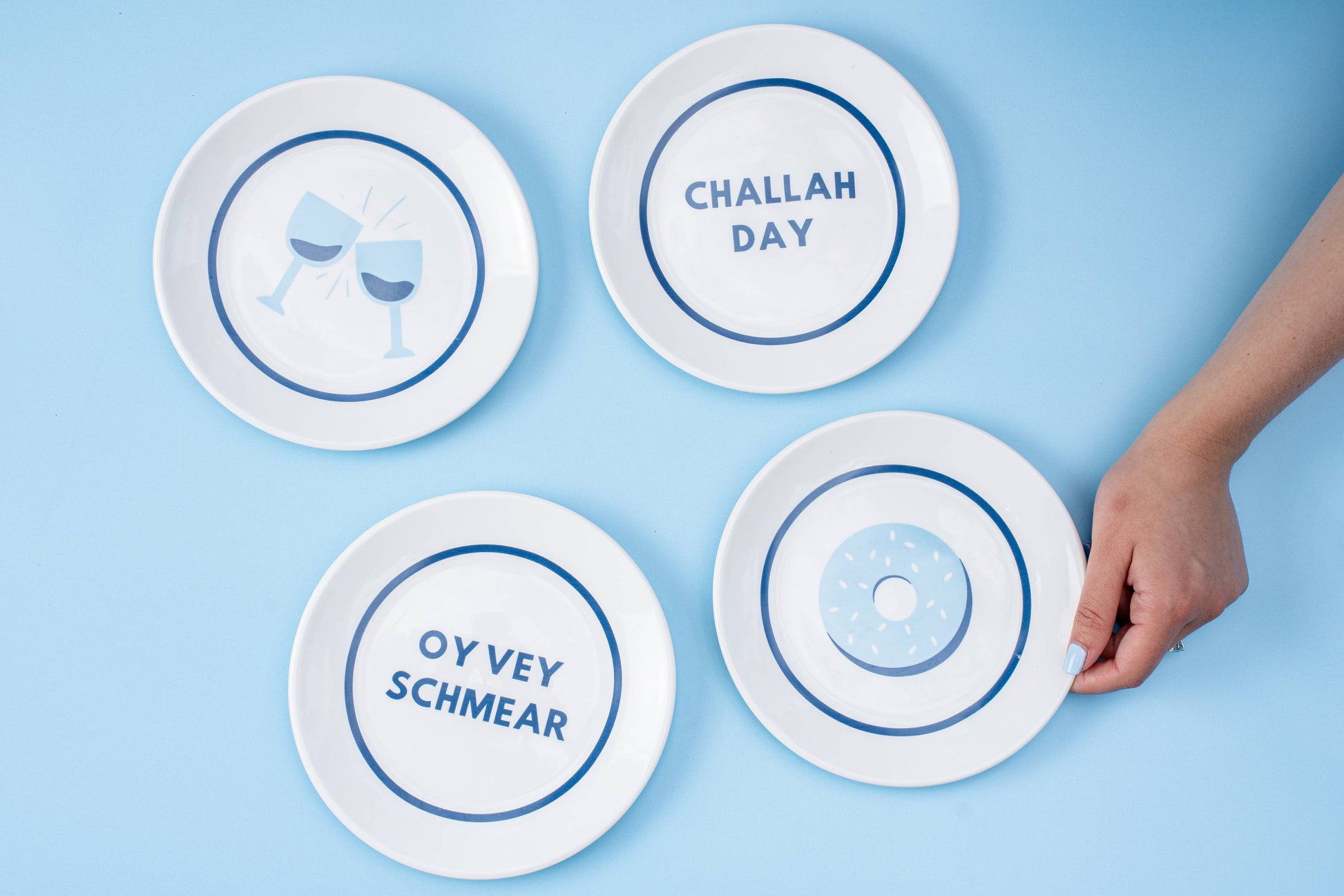 Hanukkah gift set featuring 4 porcelain nosh plates and 4 cotton/linen cocktail napkins, each with playful designs. Perfect for festive meals and gifting. Includes a custom gift box, ideal for holiday celebrations.