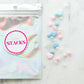 DIY Swiftie friendship bracelet kit featuring light pink and blue heart beads, glitter beads, and clear string. Comes in a silver bag with 'Lover' theme, perfect for creating two custom bracelets. Ideal for Taylor Swift fans and crafting enthusiasts.