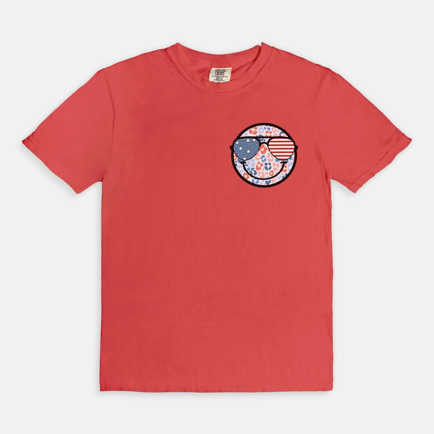 Retro smiley face sunglasses t-shirt featuring a patriotic design with American flag shades. Perfect for 4th of July celebrations, this vintage-style Comfort Colors tee is soft-washed, pre-shrunk, and available in unisex sizes. Show off 90s nostalgia with this fun and comfortable USA flag shirt, ideal for summer BBQs, fireworks, and family gatherings.