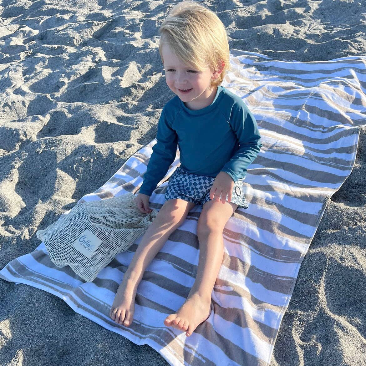 Blue brush stripe towel spread on sandy beach