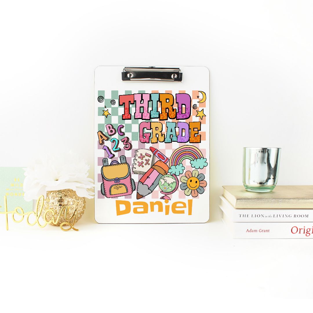 Personalized Custom Clipboard for Third Graders, featuring a cheerful design and available in various colors. Perfect as a back-to-school gift, this clipboard is ideal for organizing documents, homework assignments, and notes. It makes a great gift for teachers and teaching assistants, combining functionality with fun schoolhouse art. Customize it with your child's name for a unique touch!