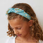Lele Sadoughi x Wicked Headband, NY Broadway Collaboration, Wicked 25th Anniversary Accessories, Glinda-Inspired Magical Wand Design, Bubble Blue Poly Blend Headband, Hand-Embellished Oval Opals & Round Crystals, 14k Gold-Plated Wand Charms, Comfort Fit Band for Ages 3-9, Trademark Logo Charm, Spot Clean, Custom Collaboration Pouch Included, Stylish & Comfortable NYC Design, High-Quality Fabrics & Hand-Sewn Trims, Iconic Wicked Accessories, Perfect Gift for Broadway Fans, Unique Collaboration Headband, Lele