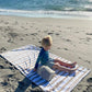 Beach flat lay featuring blue striped towel and sunscreen