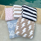 Collection of patterned towels stacked on a stone surface near a pool.