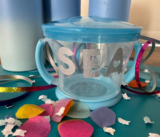Spill-proof snack pack for toddlers that holds 9 ounces of snacks, featuring a design that fits most standard cup holders. Dishwasher safe for easy cleaning.