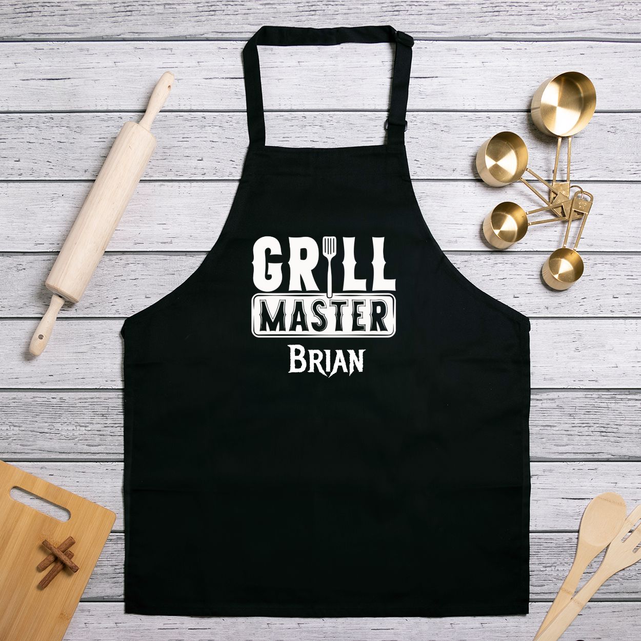 Personalized black kitchen apron with slider neck adjustment for easy sizing. Made from a 7.5 oz poly-cotton blend, featuring a one-sided 10.25"x10.25" design. Machine-washable for convenience, perfect for chefs and home cooks. Add your name for customization.