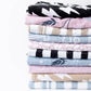 Stack of folded fabric swatches with various patterns on a white background