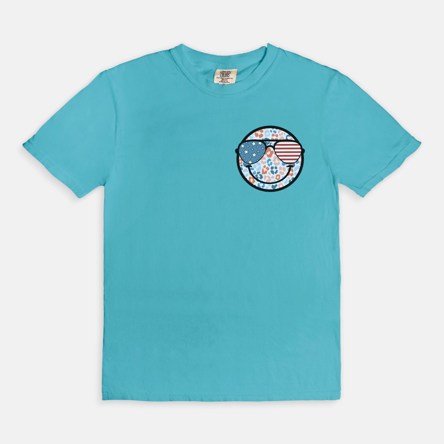 Retro smiley face sunglasses t-shirt featuring a patriotic design with American flag shades. Perfect for 4th of July celebrations, this vintage-style Comfort Colors tee is soft-washed, pre-shrunk, and available in unisex sizes. Show off 90s nostalgia with this fun and comfortable USA flag shirt, ideal for summer BBQs, fireworks, and family gatherings.