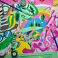 Colorful abstract painting with paint containers and brushes on a pink background