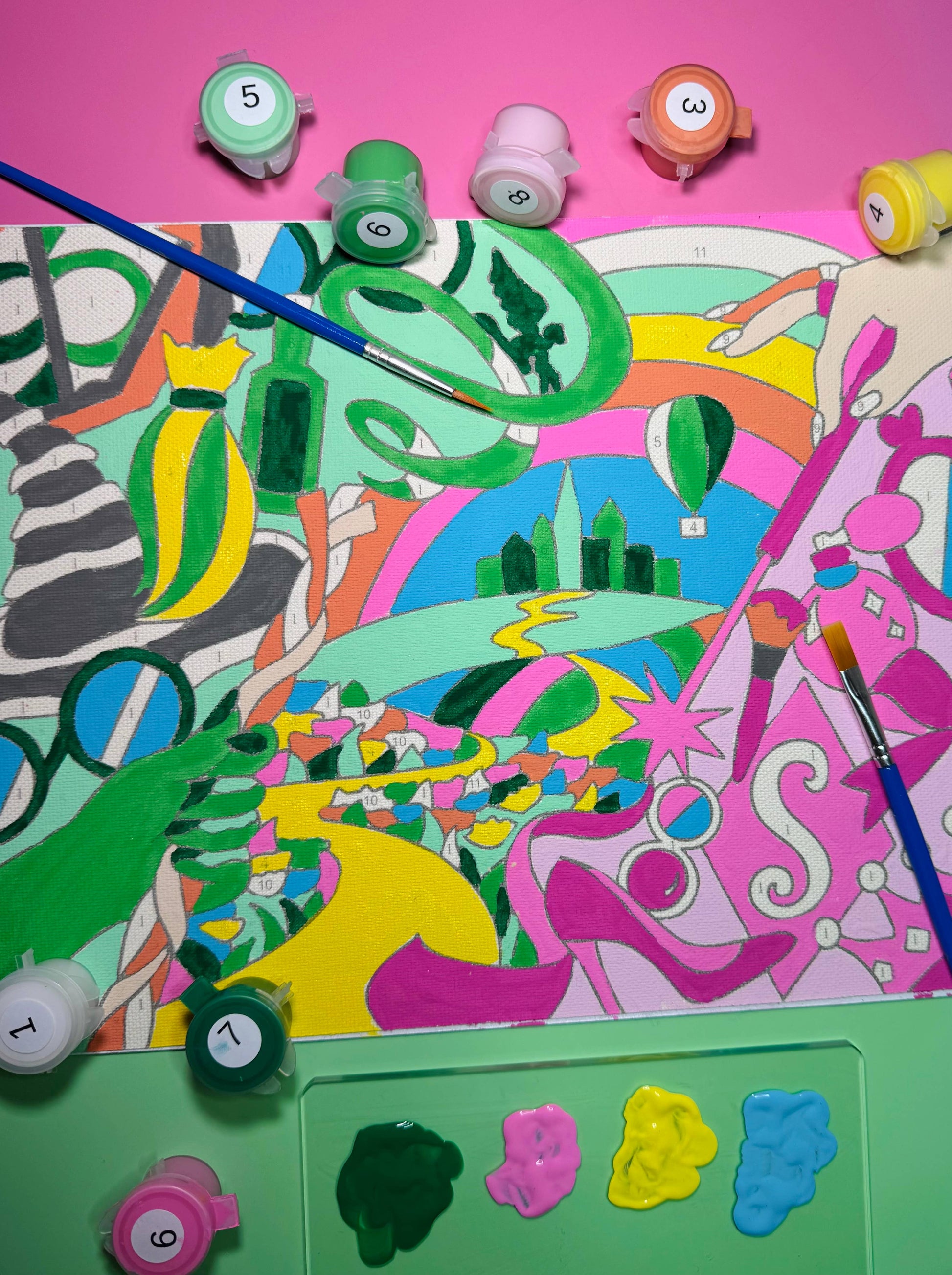 Colorful abstract painting with paint containers and brushes on a pink background