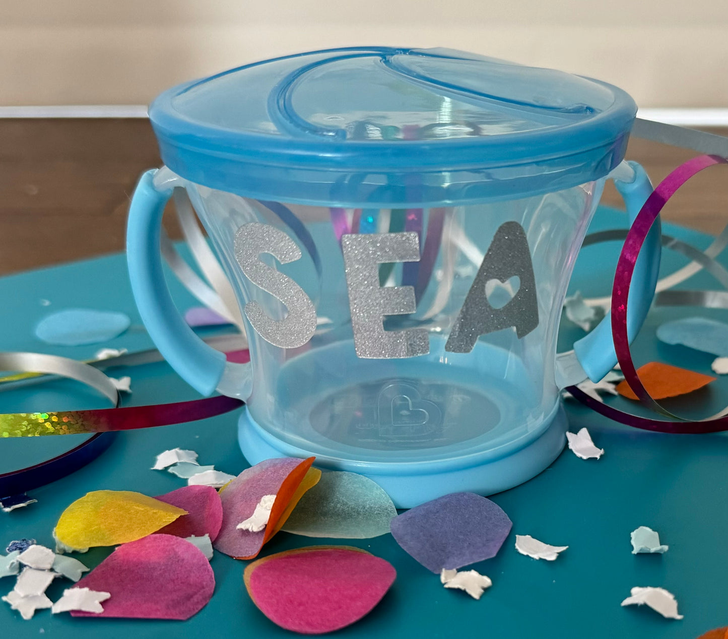 Spill-proof snack pack for toddlers that holds 9 ounces of snacks, featuring a design that fits most standard cup holders. Dishwasher safe for easy cleaning.
