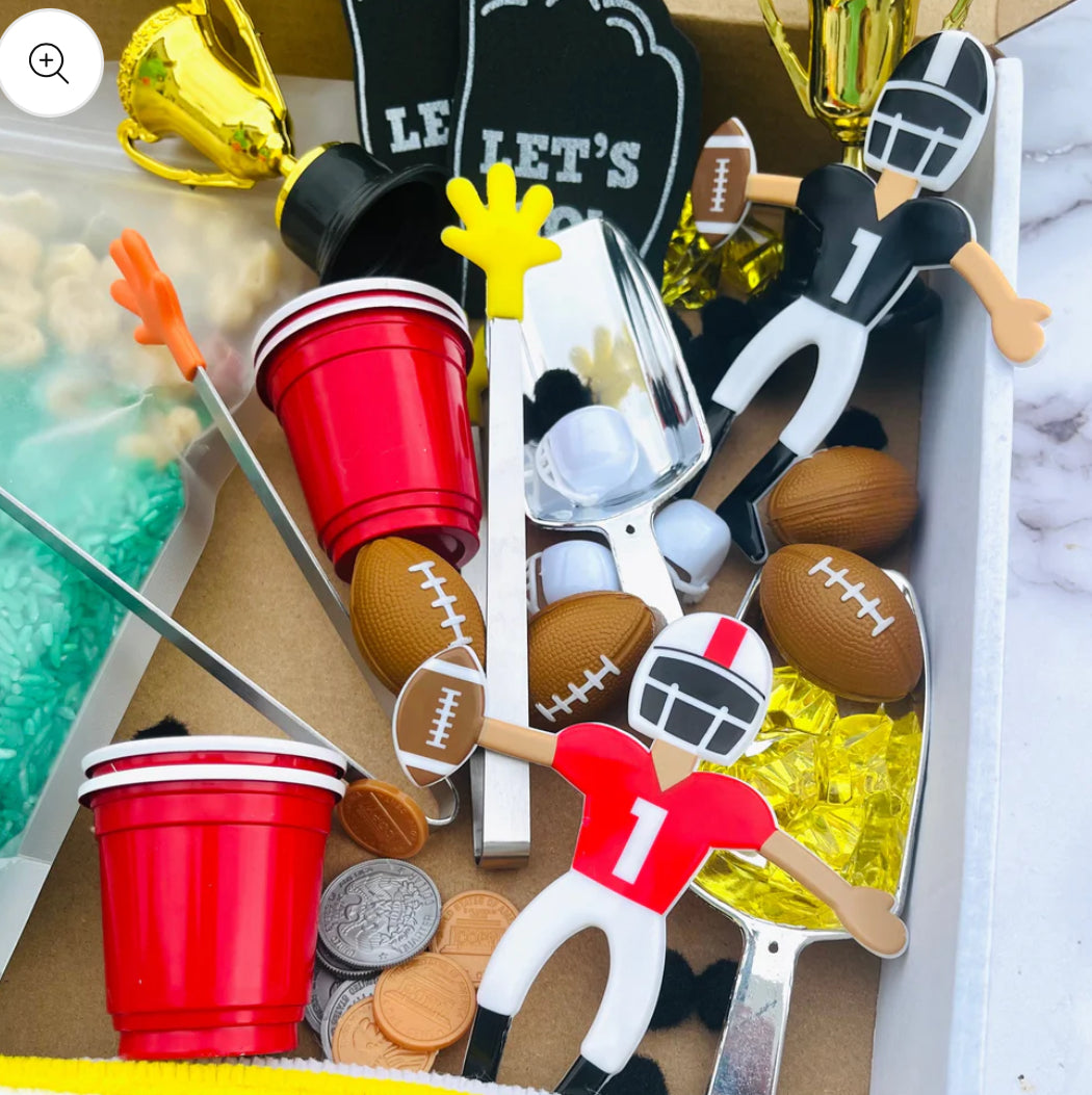 Football-themed sensory kit for kids, perfect for imaginative play. Includes mini footballs, bendable players, trophies, solo cups, foam fingers, helmets, scoops, yellow gems, pom-poms, pipe cleaners, tongs, coins, green rice, and football pasta. Encourages creativity and fine motor skills. Ages 3+, adult supervision recommended. Bin not included. Warning: small parts choking hazard.