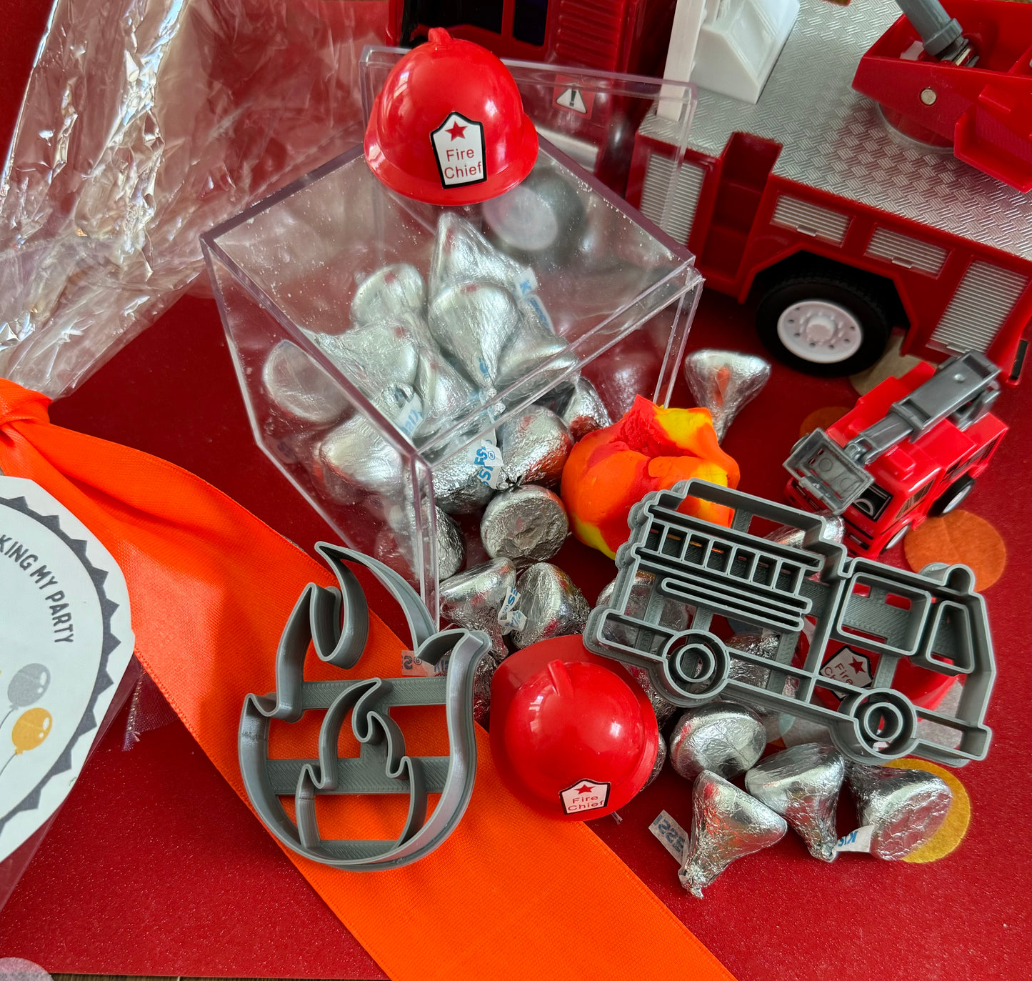 Delight in our Firetruck Themed candy favor, perfect for birthdays and firehouse play dates. This magical treat comes in a perfectly sized square plastic box filled with chocolate 'kisses' themed with firetruck labels. Each box is wrapped in cellophane and can include a thank you label. Explore more candy container options. Ideal for fire truck, firefighter, and tractor-themed parties, ensuring a delicious and fun addition to your celebration.