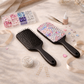 Two black hairbrushes with decorative beads on a light surface with crafting supplies.