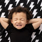 Child lying on a black and white patterned blanket