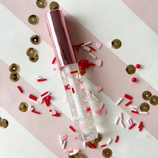 Strawberry-flavored heart wand lip gloss with red & pink confetti, moisturizing, perfect Valentine gift.