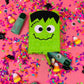 Mini Frankenstein piñata, measuring 5 inches tall, perfect for Halloween indoor decoration or party favor. Features a pull trap door for easy filling. A fun and spooky addition to Halloween events or table decor