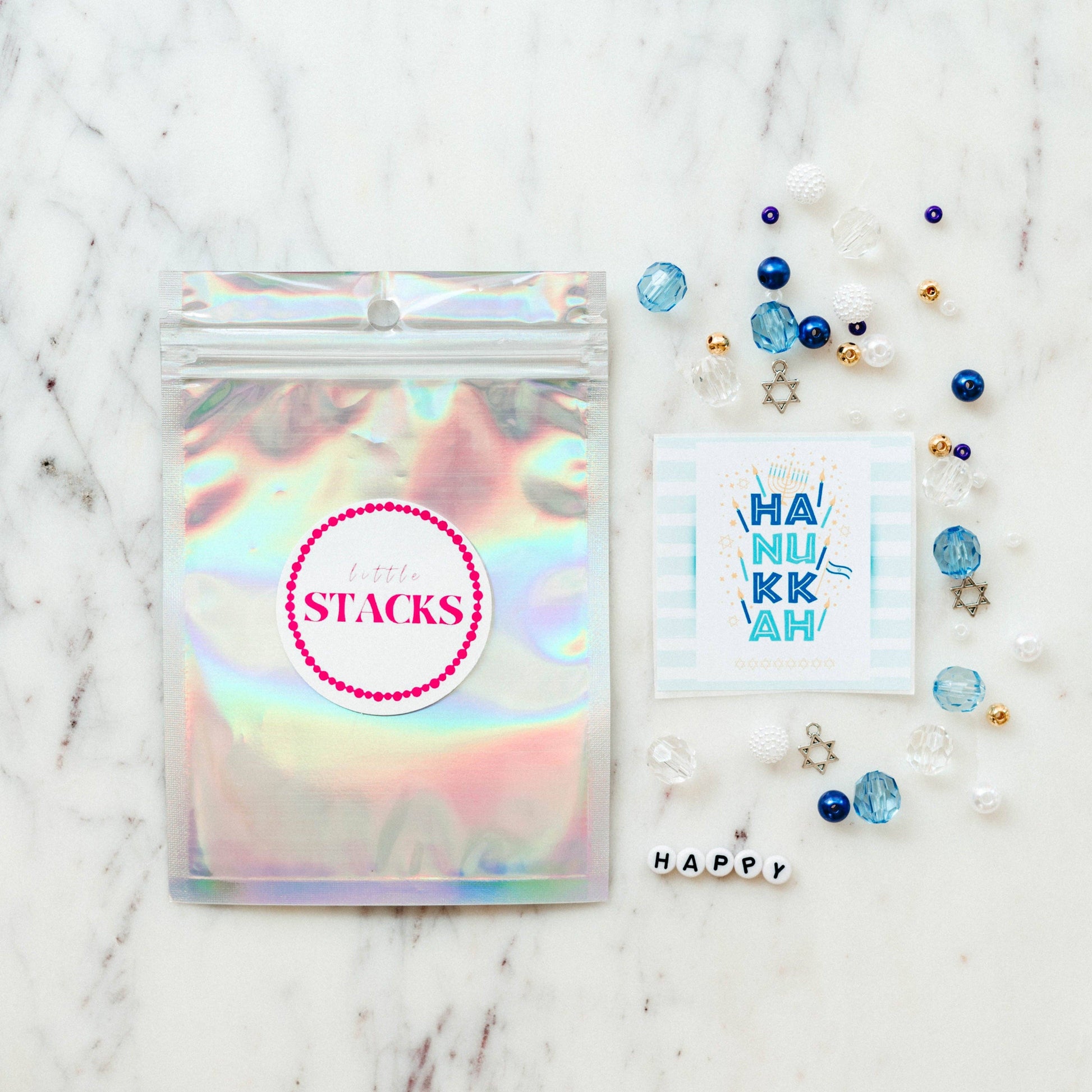 Create a festive Hanukkah stack with this bracelet kit featuring Star of David charms, pearls, and colorful beads. Makes 2+ bracelets (10-year-old sizing). WARNING: Small parts, choking hazard for children under 3. Adult supervision recommended.