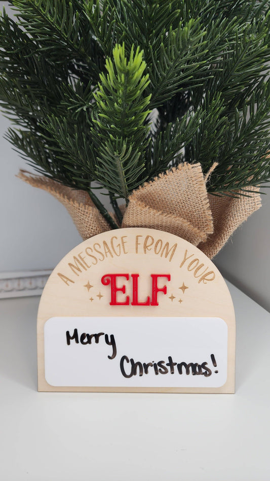 A personalized Elf on the Shelf dry-erase board made from 1/8" birch and acrylic. The board features a laser-cut and engraved design, perfect for adding creative messages from your elf this Christmas. Dry erase marker not included. Slight imperfections may be present due to the handmade nature of the product.
