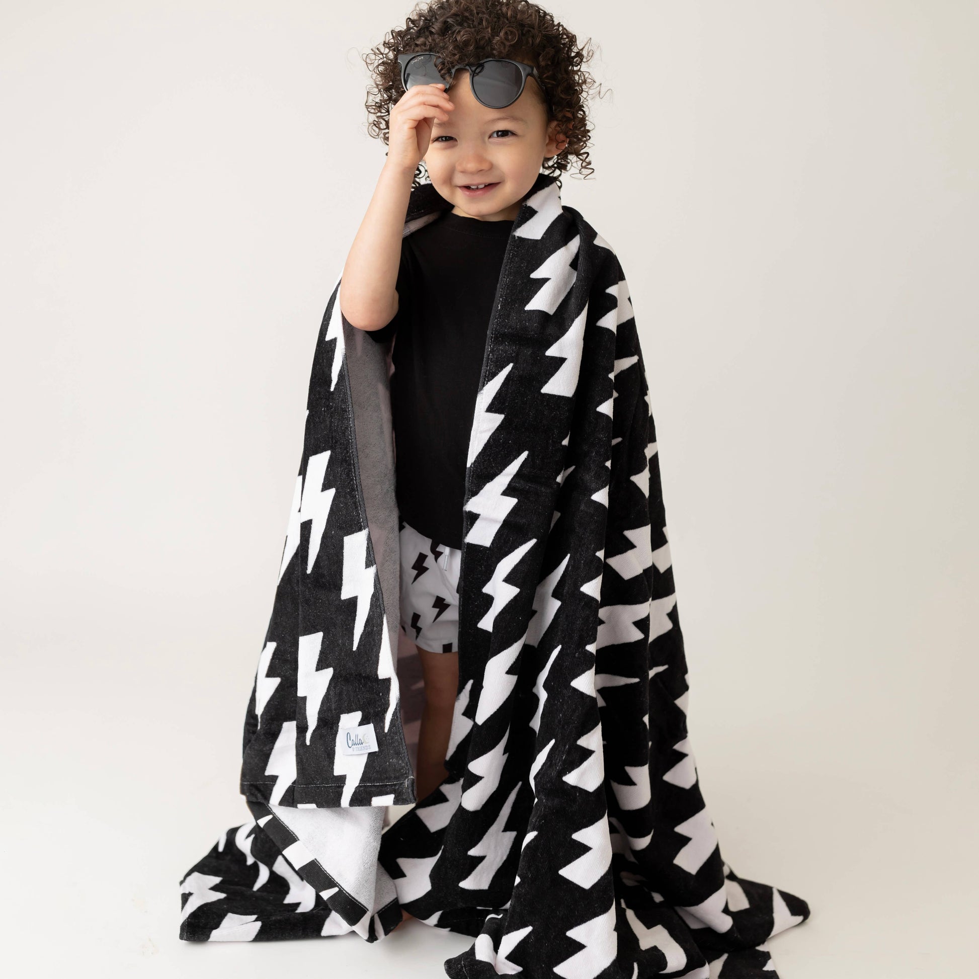 Child wrapped in a black and white patterned blanket on a plain background