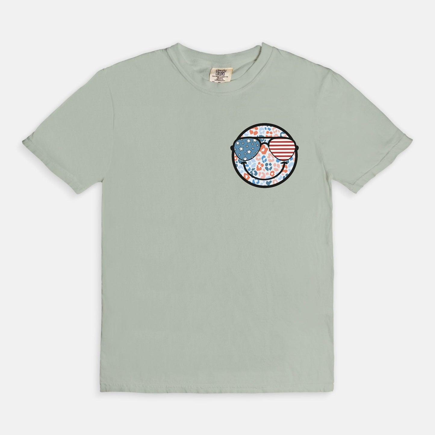 Retro smiley face sunglasses t-shirt featuring a patriotic design with American flag shades. Perfect for 4th of July celebrations, this vintage-style Comfort Colors tee is soft-washed, pre-shrunk, and available in unisex sizes. Show off 90s nostalgia with this fun and comfortable USA flag shirt, ideal for summer BBQs, fireworks, and family gatherings.