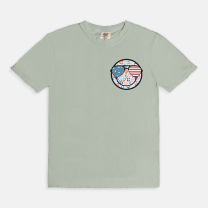 Retro smiley face sunglasses t-shirt featuring a patriotic design with American flag shades. Perfect for 4th of July celebrations, this vintage-style Comfort Colors tee is soft-washed, pre-shrunk, and available in unisex sizes. Show off 90s nostalgia with this fun and comfortable USA flag shirt, ideal for summer BBQs, fireworks, and family gatherings.