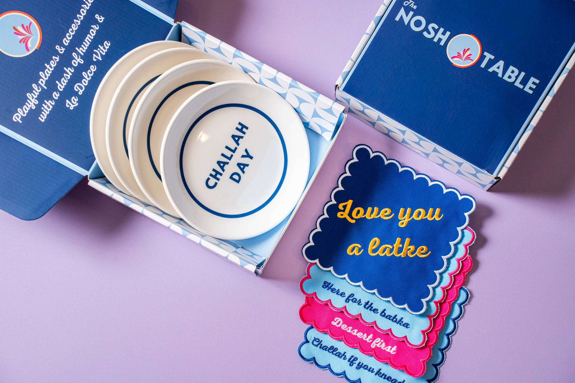 Hanukkah gift set featuring 4 porcelain nosh plates and 4 cotton/linen cocktail napkins, each with playful designs. Perfect for festive meals and gifting. Includes a custom gift box, ideal for holiday celebrations.