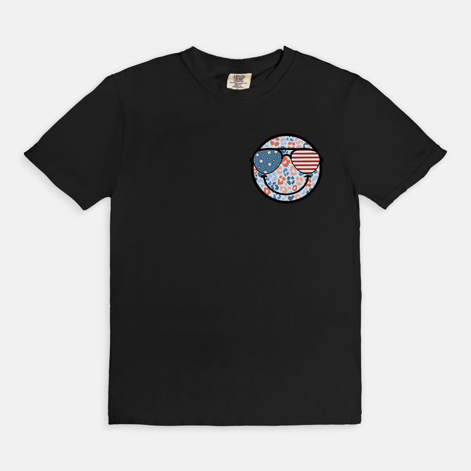 Retro smiley face sunglasses t-shirt featuring a patriotic design with American flag shades. Perfect for 4th of July celebrations, this vintage-style Comfort Colors tee is soft-washed, pre-shrunk, and available in unisex sizes. Show off 90s nostalgia with this fun and comfortable USA flag shirt, ideal for summer BBQs, fireworks, and family gatherings.