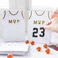 Basketball treat bags set, including 8 jersey-style bags measuring 5" x 8" x 2.5". Features gold number stickers and twine for a fun party accessory. Perfect for kids' basketball-themed parties, ensuring a slam dunk with kids and parents alike.