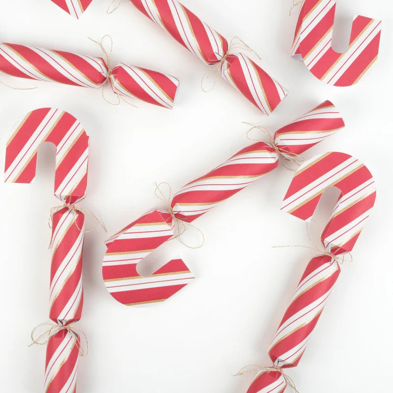 Festive candy cane crackers with gold glitter, metallic bows, party hats, jokes, and unique gifts inside.
