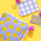 Medium smiley pouches with embroidered design, gold zipper accents, and pom-pom details.